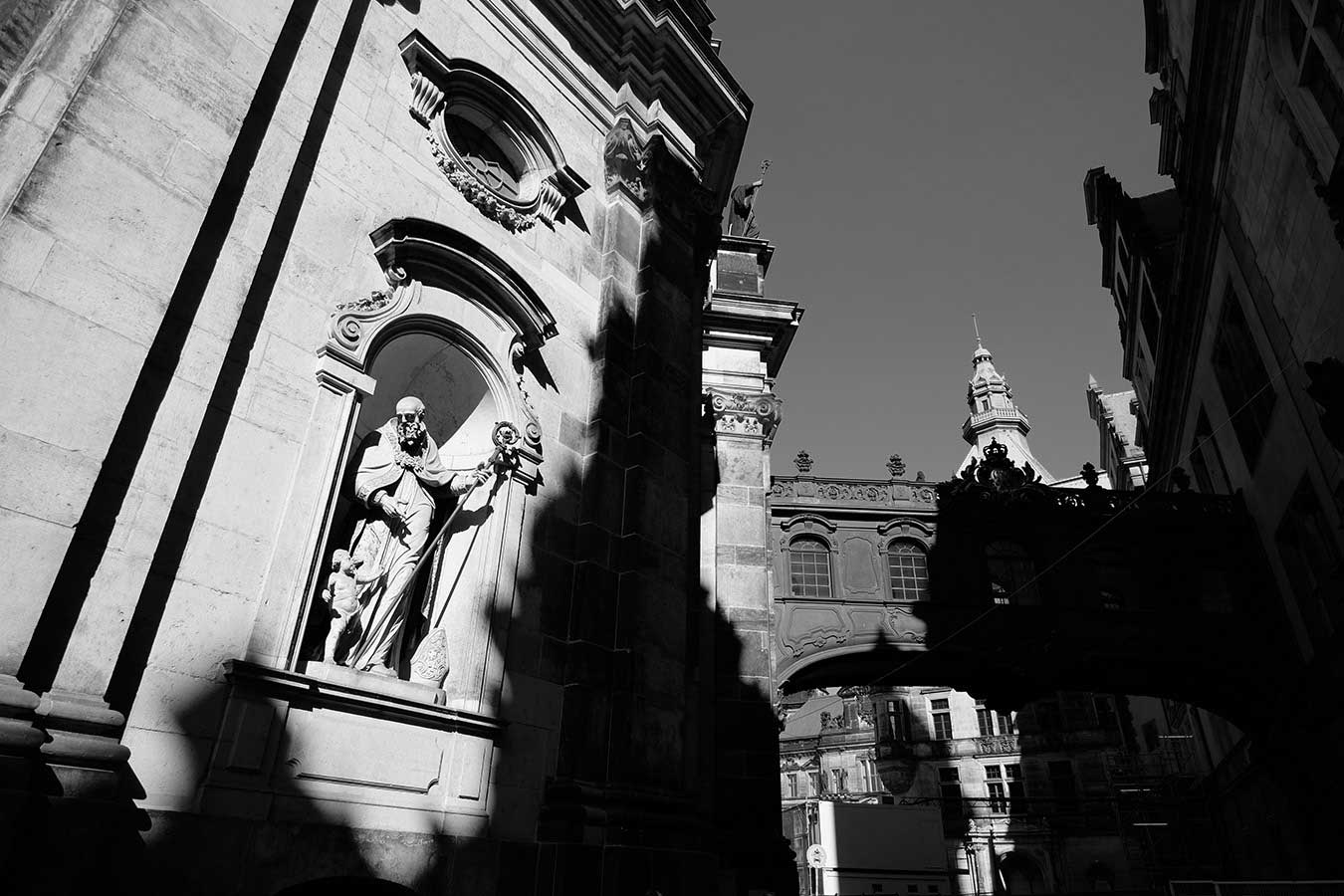 Black and white photo in Dresden, Germany. Old church facade with a statue under an arch.